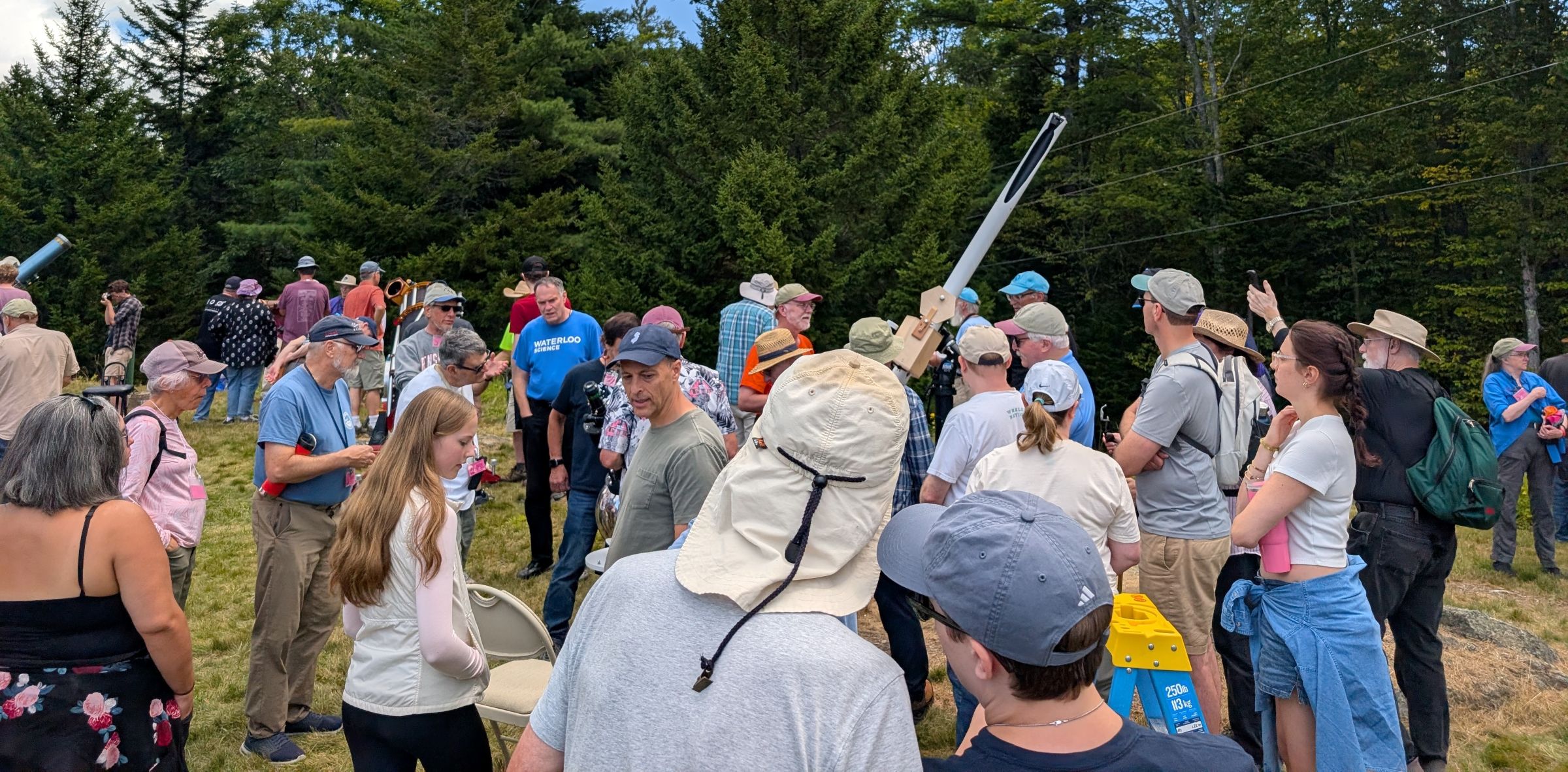 A crowd gathered around telescopes on the Stellafane telescope field